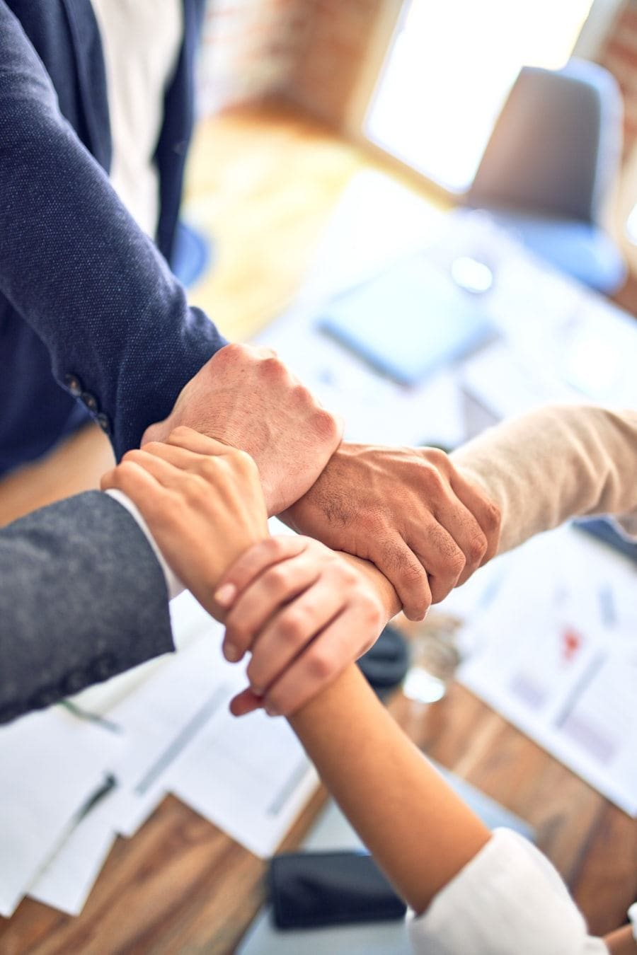 A team joining hands over a desk